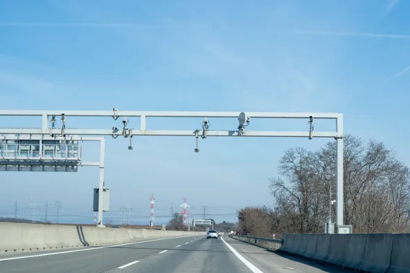 Slovakia motorway enforcement gantry with multiple ANPR cameras and satellite dish spanning all lanes on D2 near Bratislava, used for e-vignette and toll compliance checking, clear blue sky, February 2026